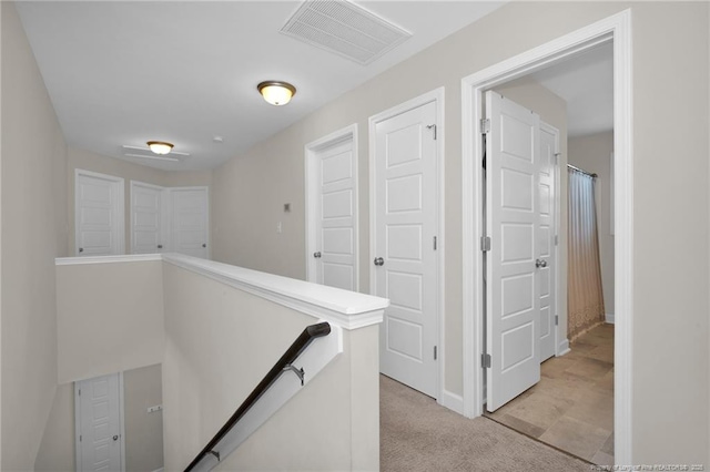corridor with light colored carpet, baseboards, an upstairs landing, and visible vents