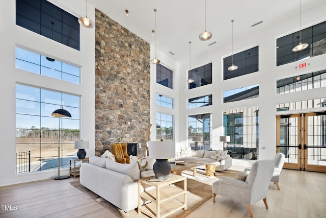 living area with plenty of natural light, a towering ceiling, and wood finished floors