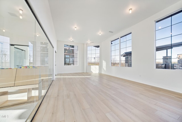 unfurnished living room with baseboards and light wood-type flooring