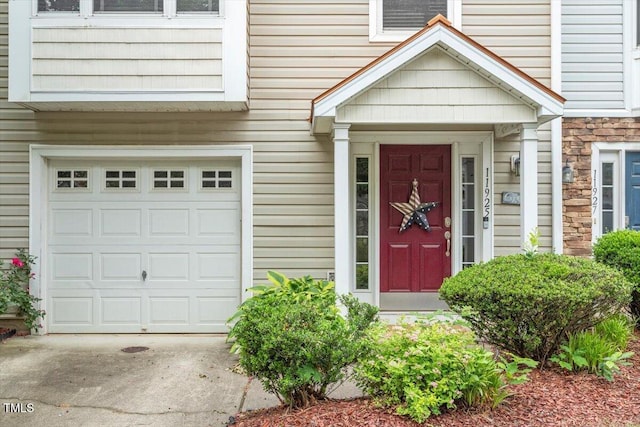 11925 Field Towne Ln, Raleigh, NC 27614 - view of exterior entry with stone siding, an attached garage, and driveway