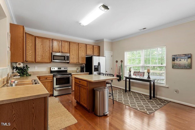11925 Field Towne Ln, Raleigh, NC 27614 - kitchen featuring appliances with stainless steel finishes, a sink, wood finished floors, light countertops, and a breakfast bar area