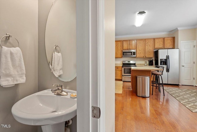 11925 Field Towne Ln, Raleigh, NC 27614 - kitchen featuring appliances with stainless steel finishes, a breakfast bar, crown molding, light wood-style flooring, and a sink