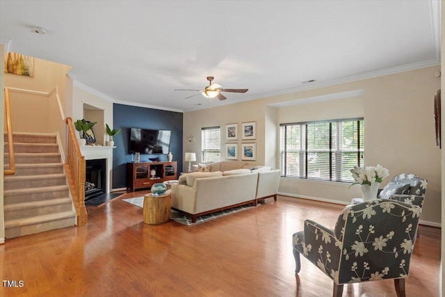 11925 Field Towne Ln, Raleigh, NC 27614 - living area featuring a ceiling fan, crown molding, stairs, wood finished floors, and a fireplace with flush hearth