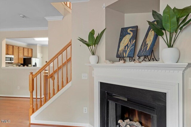 11925 Field Towne Ln, Raleigh, NC 27614 - detailed view of stainless steel microwave, refrigerator with ice dispenser, a fireplace, ornamental molding, and wood finished floors
