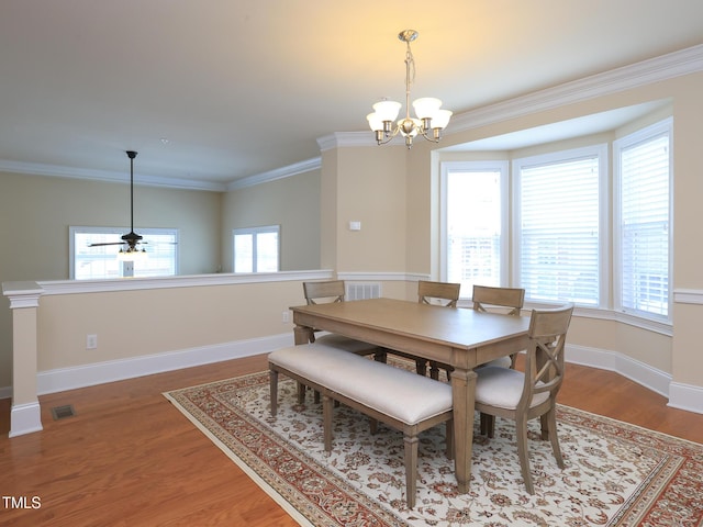 dining area with a chandelier, crown molding, wood finished floors, baseboards, and a ceiling fan