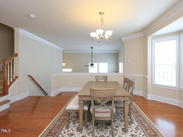 dining area featuring wood finished floors, plenty of natural light, a chandelier, ornamental molding, and baseboards