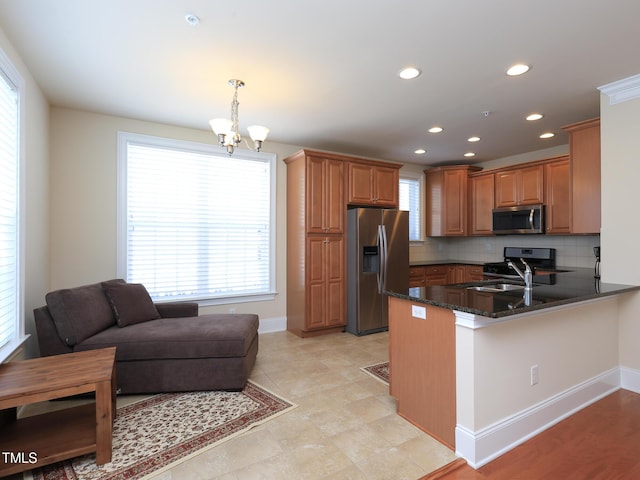 kitchen with appliances with stainless steel finishes, a peninsula, tasteful backsplash, recessed lighting, and dark stone countertops