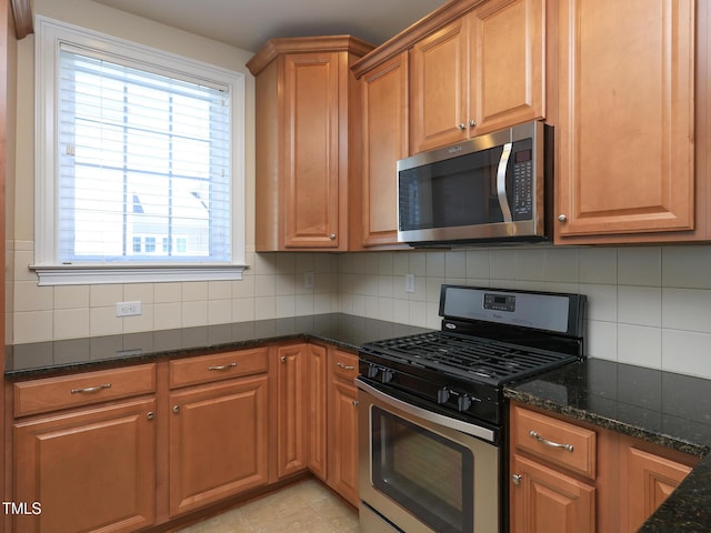 kitchen featuring appliances with stainless steel finishes, plenty of natural light, dark stone countertops, and decorative backsplash