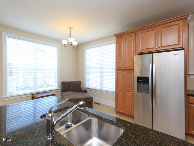 kitchen featuring stainless steel fridge with ice dispenser, a sink, healthy amount of natural light, and a chandelier