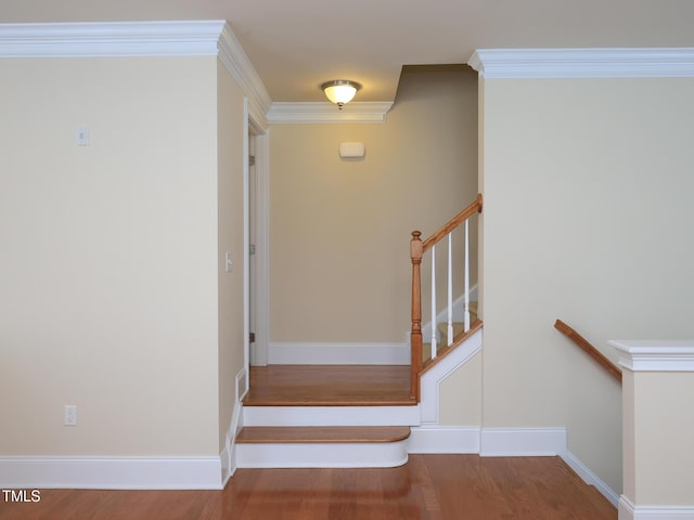 staircase featuring wood finished floors, crown molding, and baseboards