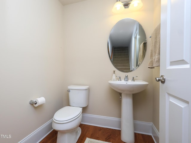 bathroom featuring toilet, wood finished floors, baseboards, and a sink