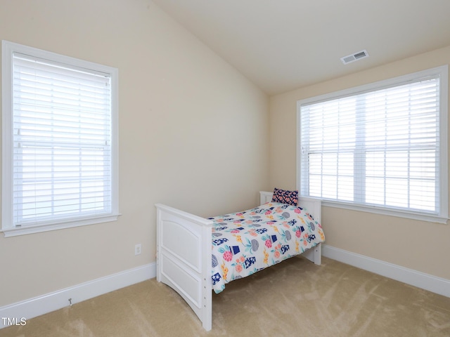 bedroom with light colored carpet, multiple windows, vaulted ceiling, and baseboards