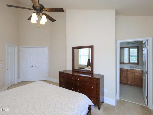 bedroom with a sink, a high ceiling, baseboards, multiple windows, and connected bathroom