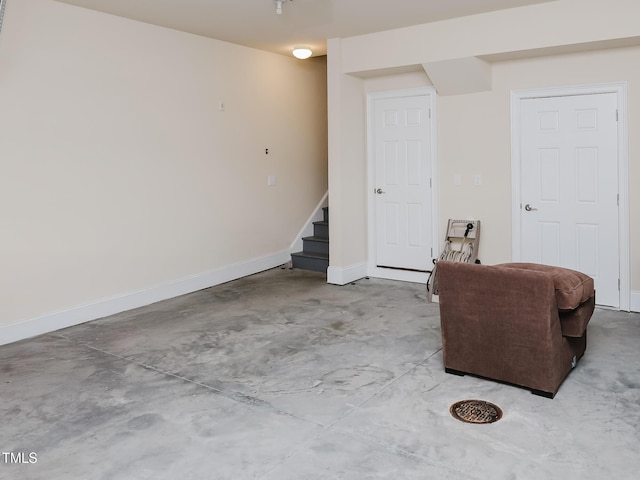 sitting room featuring stairs, concrete flooring, and baseboards