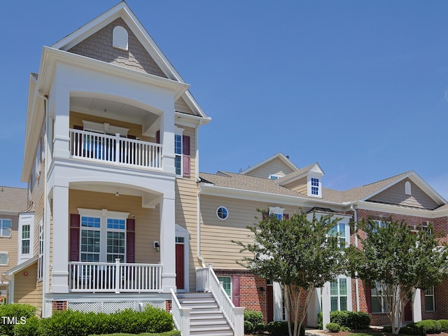 townhome / multi-family property featuring a balcony, brick siding, and a porch