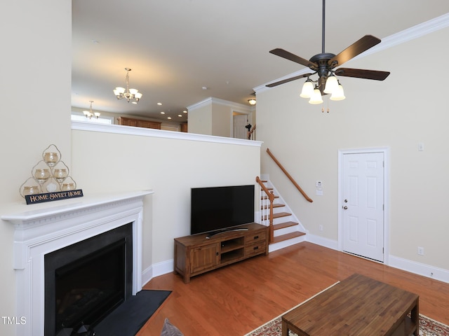 living area featuring a chandelier, a fireplace with flush hearth, a ceiling fan, wood finished floors, and stairs