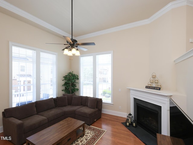 living area with a fireplace with flush hearth, ceiling fan, ornamental molding, wood finished floors, and baseboards