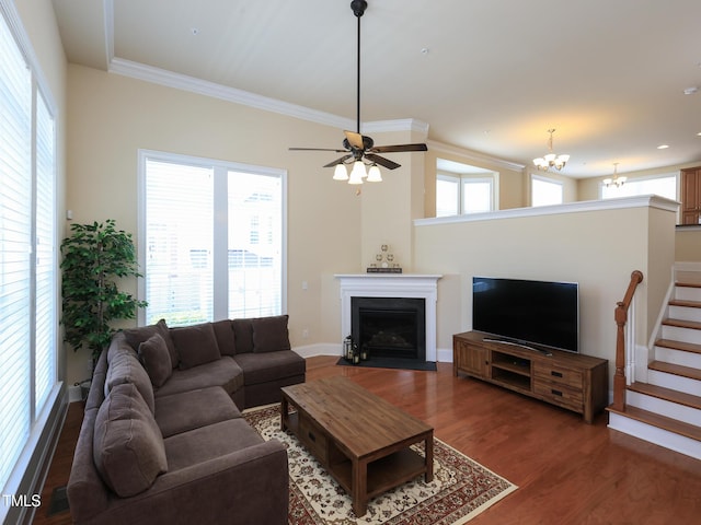 living room featuring wood finished floors, a fireplace with flush hearth, a chandelier, ornamental molding, and baseboards