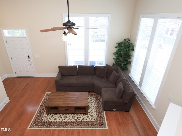 living area with wood finished floors, a ceiling fan, and baseboards