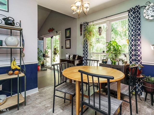 dining room with a chandelier, lofted ceiling, and wood finished floors