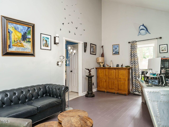 living room featuring baseboards, wood finished floors, and a towering ceiling