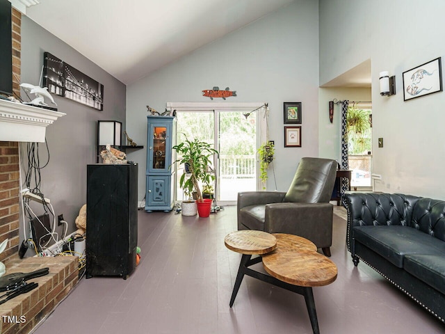 sitting room with a brick fireplace and high vaulted ceiling