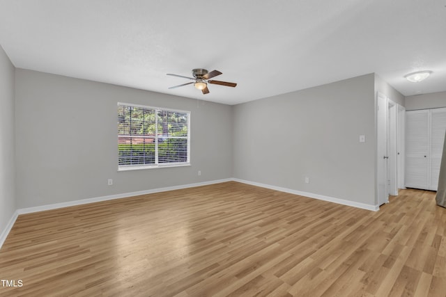 unfurnished room with ceiling fan, light wood-style floors, and baseboards