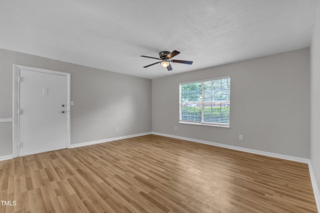 spare room with ceiling fan, light wood-style floors, and baseboards