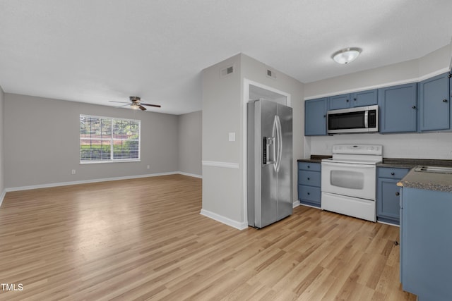 kitchen with stainless steel appliances, blue cabinetry, dark countertops, and light wood-type flooring