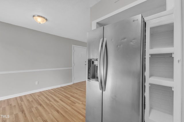 kitchen with stainless steel refrigerator with ice dispenser, light wood finished floors, and baseboards
