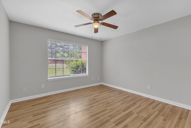 empty room with light wood-style floors, a ceiling fan, and baseboards