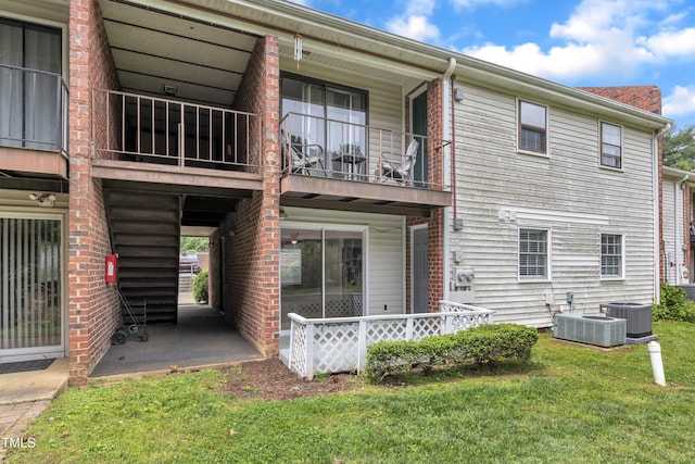 rear view of property with a balcony and a lawn