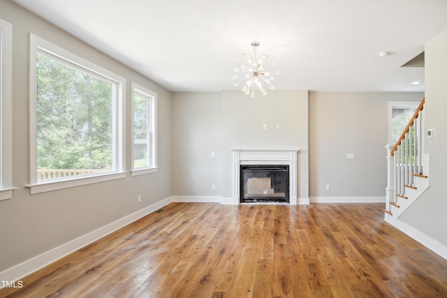509 Olive Branch Rd, Durham, NC 27703 - unfurnished living room featuring a chandelier, plenty of natural light, wood finished floors, and baseboards