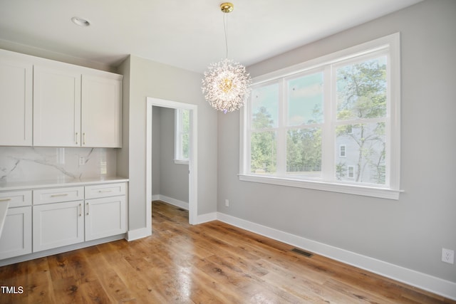 509 Olive Branch Rd, Durham, NC 27703 - unfurnished dining area featuring baseboards, a chandelier, and light wood-type flooring
