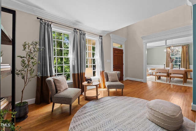 sitting room with light wood-style flooring, plenty of natural light, a chandelier, and ornamental molding