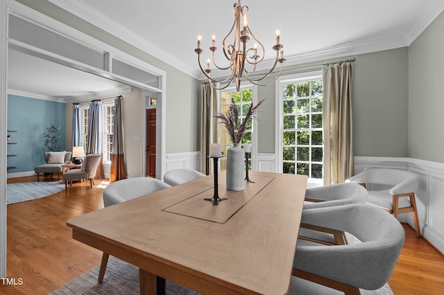 dining area featuring a chandelier, crown molding, light wood finished floors, and wainscoting