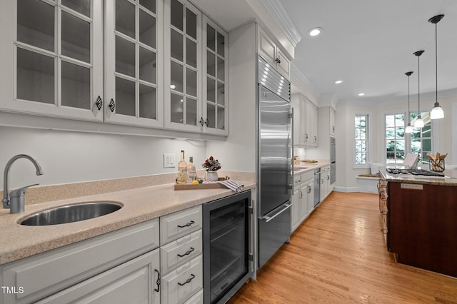 kitchen with wine cooler, stainless steel appliances, a sink, glass insert cabinets, and light countertops
