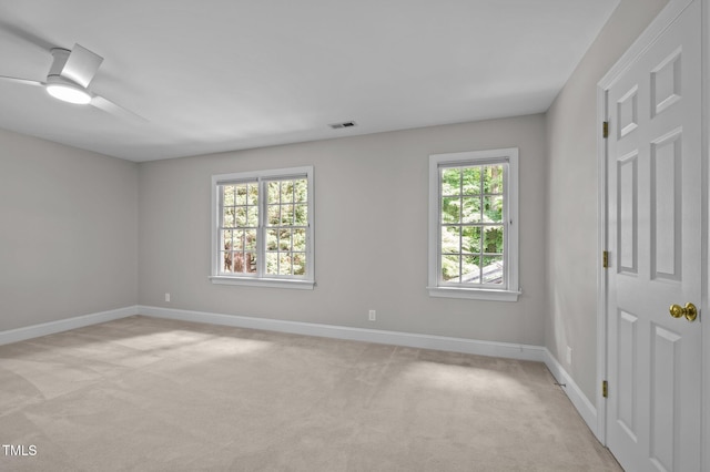 unfurnished room featuring baseboards, light colored carpet, and ceiling fan