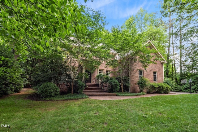 view of property hidden behind natural elements featuring brick siding and a front yard