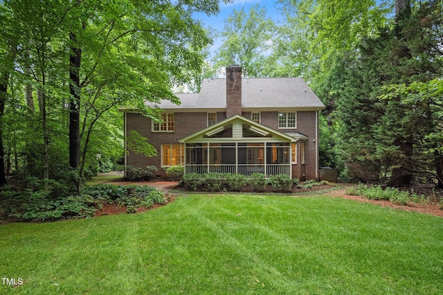 rear view of property with a sunroom, a chimney, and a yard