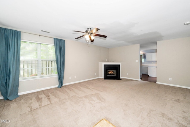 unfurnished living room featuring ceiling fan, carpet flooring, baseboards, and a fireplace with flush hearth
