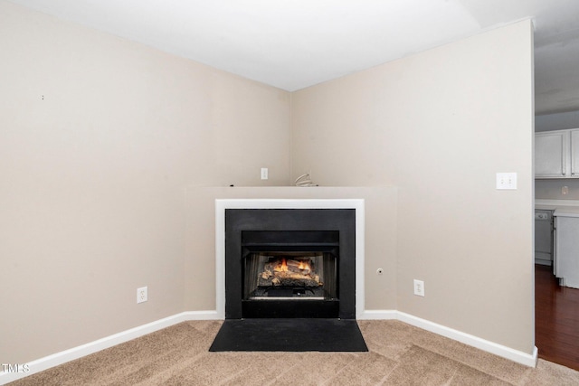 detailed view of baseboards, a fireplace with flush hearth, and carpet flooring