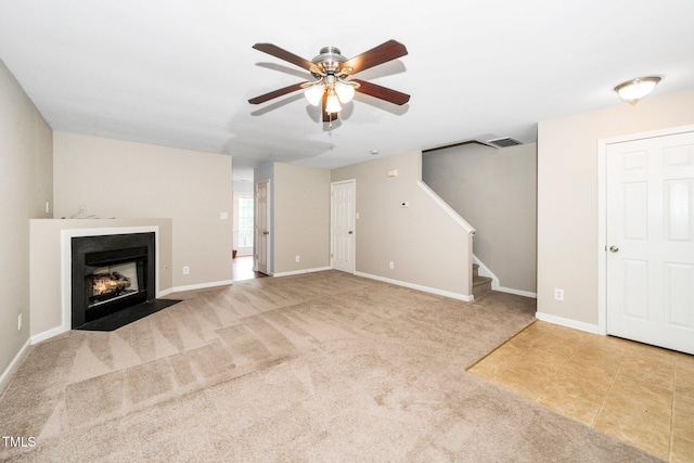 unfurnished living room featuring ceiling fan, stairs, carpet, a fireplace with flush hearth, and baseboards