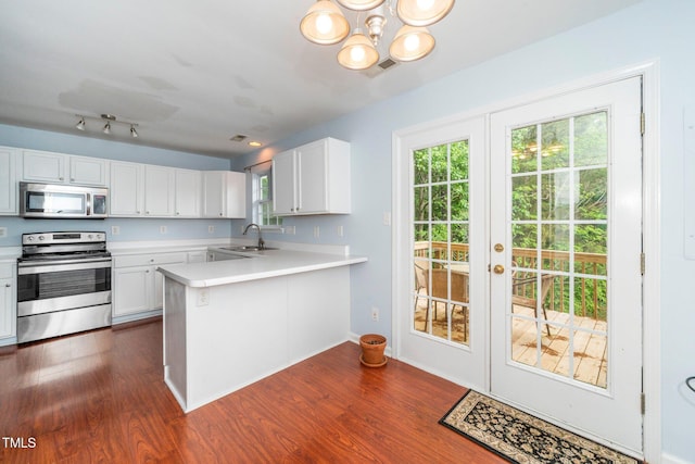 kitchen with appliances with stainless steel finishes, a sink, light countertops, and dark wood-style floors