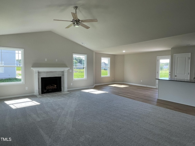unfurnished living room with ceiling fan, wood finished floors, baseboards, and a tile fireplace