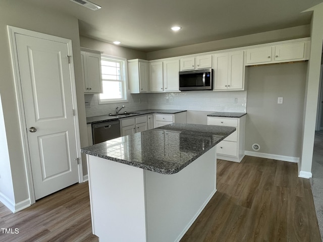 kitchen with baseboards, appliances with stainless steel finishes, a sink, and dark wood-type flooring