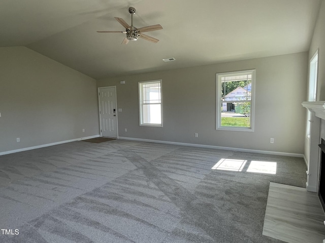 unfurnished living room with carpet flooring, a ceiling fan, a fireplace with flush hearth, visible vents, and lofted ceiling