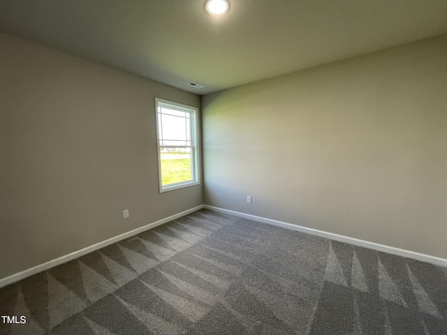 unfurnished room with dark colored carpet, baseboards, and visible vents