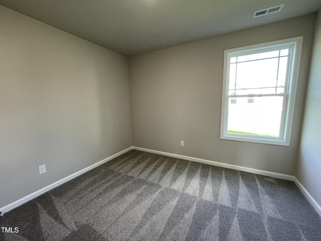 unfurnished room featuring baseboards, visible vents, and dark carpet