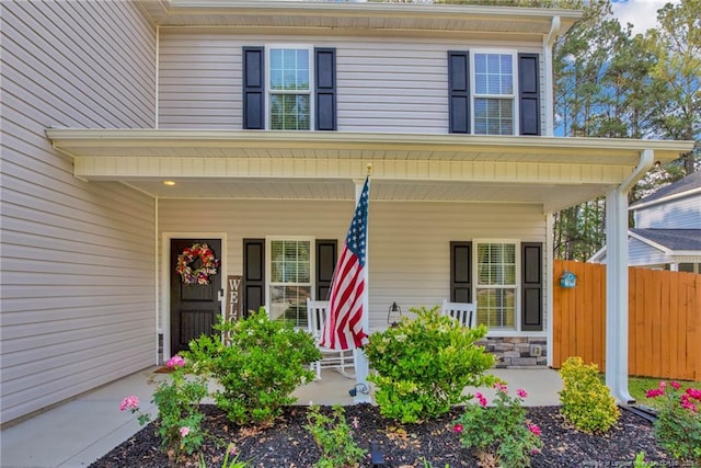 entrance to property with a porch and fence